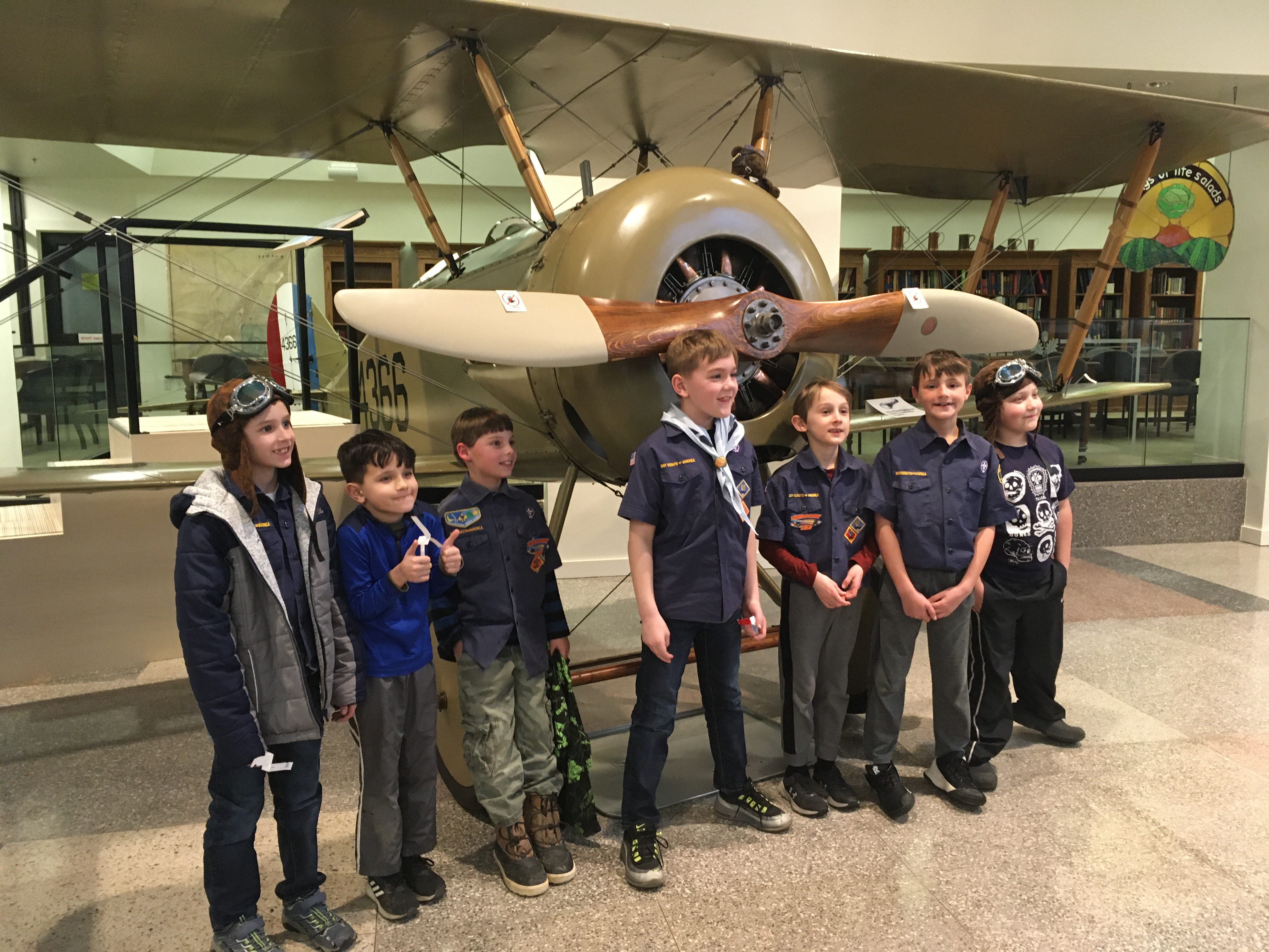 Image of a group of children standing in front of the Tommy Morse plane in the exhibit hall