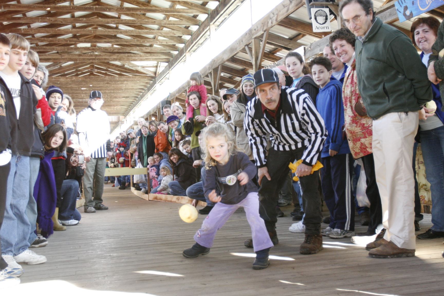 Image of a child curing a rutabaga down the farmers market with a referee and a crowd lining the path