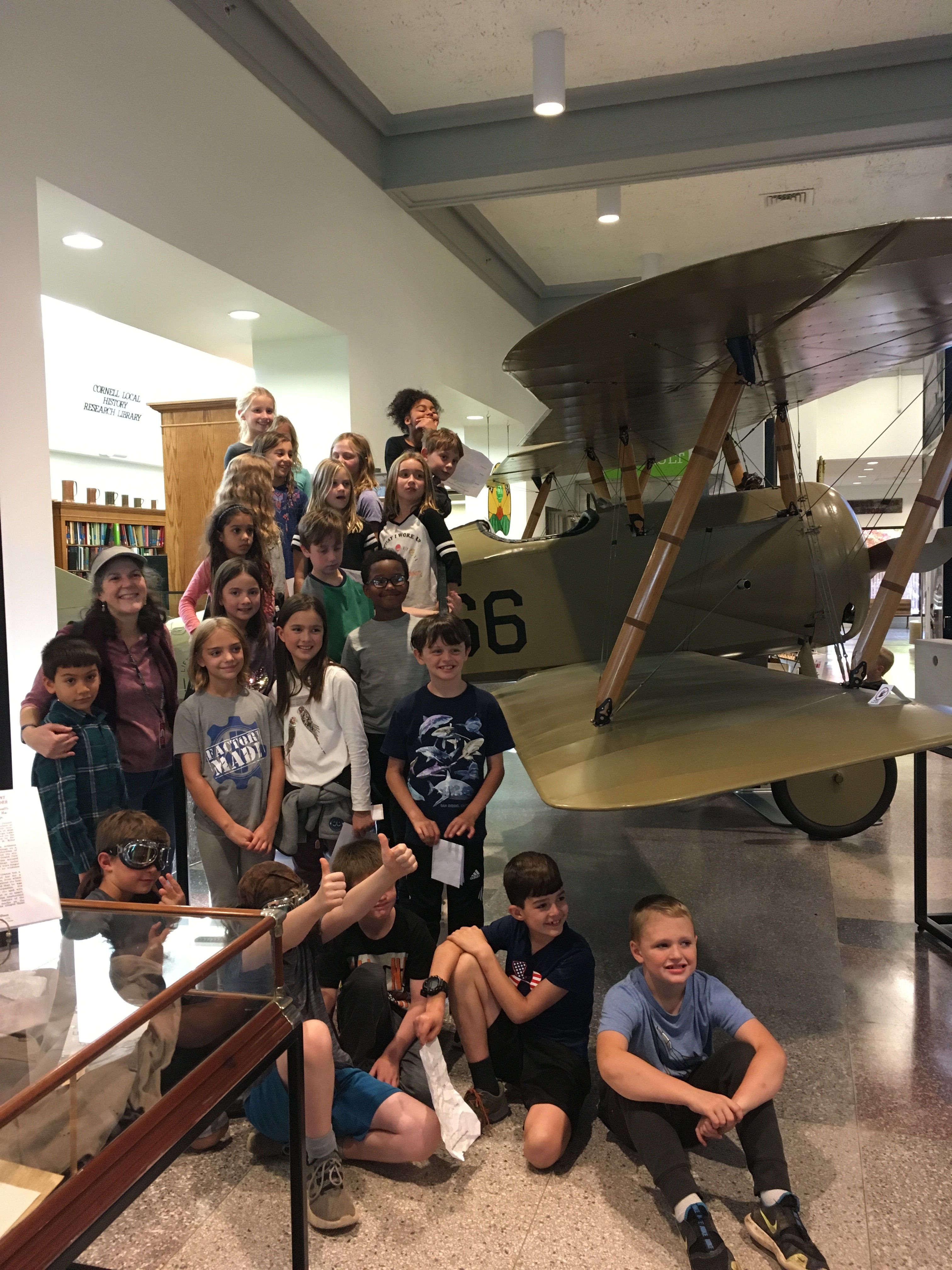 A photo of a large group of students gathered around the Tommy Plane.